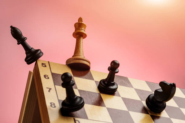 as peças de xadrez preto atacam a rainha branca na beira do tabuleiro de xadrez. conceito de luta competitiva na carreira. - chess defending chess piece chess board - fotografias e filmes do acervo