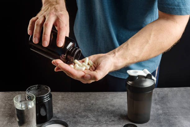 athlete takes supplements. Capsules with amino acid on the palm close-up. athlete takes supplements. Capsules with amino acid on the palm close-up. bodybuilder stock pictures, royalty-free photos & images