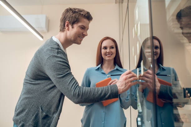 istock Man writing notes on wall and woman with tablet 1367954962