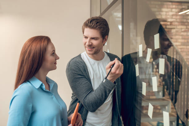 istock Man near wall with sticky notes looking at woman 1367954970