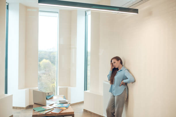 istock Woman standing near wall looking thoughtfully at table 1367955030