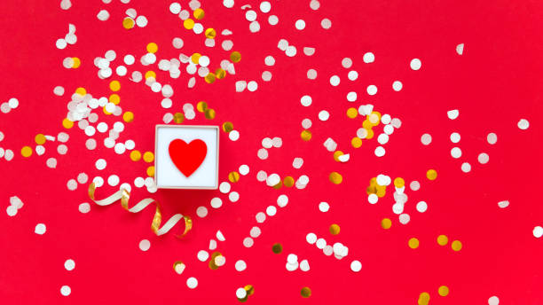 istock little red heart in box on red background with confetti 1367958613