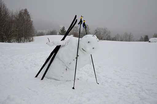 a big snowman has a sloping body that looks like he is falling, not limping, and has back pain. going away the winter is over. forward bend, back pain, tilted