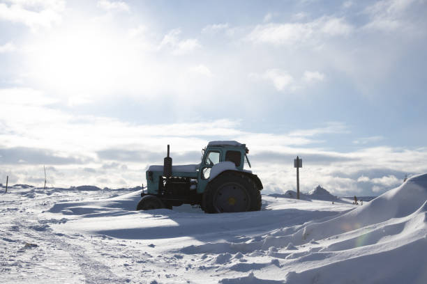 istock Tractor on a snow-covered field against a cloudy sky. 1367960940