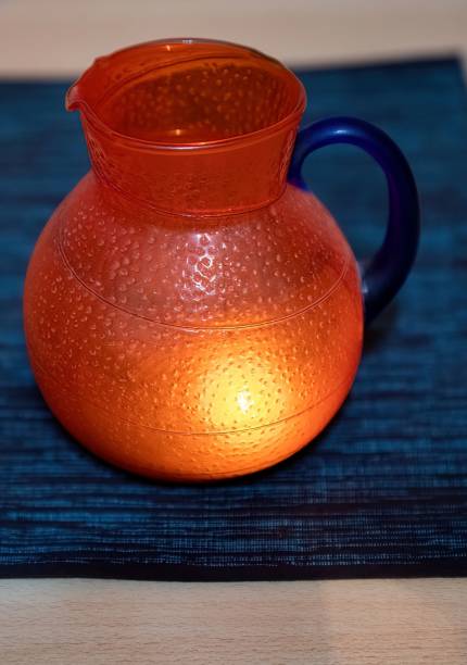 one orange colored glass jug on a table illuminated