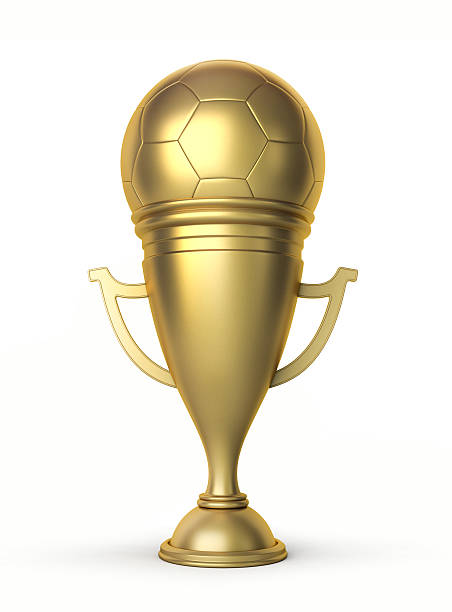 Football winner cup with a golden soccer ball in the light of spotlights on the green grass field of the stadium