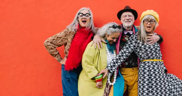 Photo of Vibrant senior citizens having fun against a red background