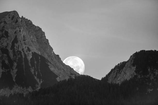 Moon descending behind mountains in the morning, black and white