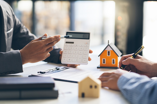 Modelo de la casa con el agente y el cliente discutiendo por contrato para comprar, obtener seguros o préstamos inmobiliarios o propiedades. photo