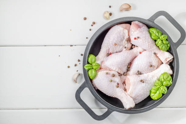 Raw uncooked chicken drumsticks. Raw butchered chicken meat with fresh herbs ready for cooking. stock photo