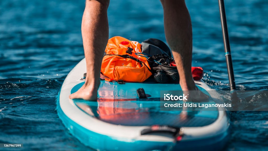 Young athletic man paddling on a SUP stand up paddle board in blue water sea in Montenegro Paddleboard Stock Photo