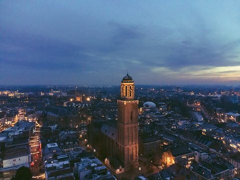 Peperbus nighttime drone view in the city of Zwolle, Overijssel during a cold winter evening. The illuminated church tower stands out against the sunset in the sky with the downtown district of Zwolle in the background.