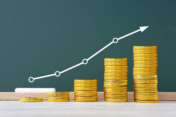 istock Money gradually piled highly and graph and arrow drawn on black board 1367970120