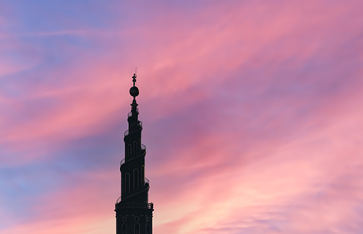 Large church spire silhouette on a colorful evening sky.