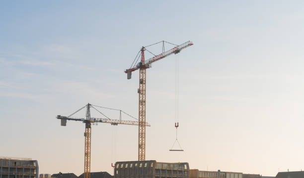 istock Tall tower cranes working at an urban construction site. 1367972204