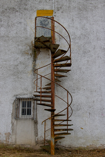 Old rusty spiral staircase leading to a closed door outside a old building