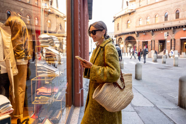 Woman near the showcase of the shop with luxury clothes on street in Bologna stock photo