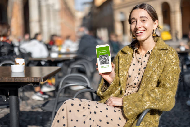 Woman showing green pass at outdoor cafe stock photo