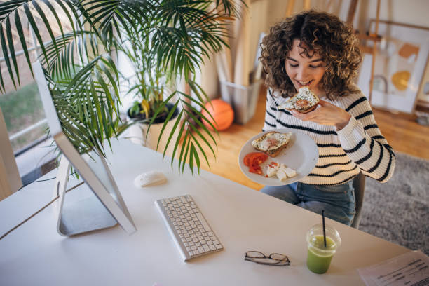 istock Woman eating breakfast in office 1367974930