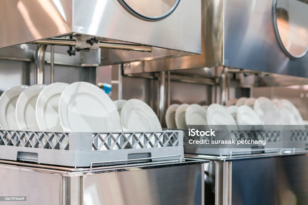 many white plate on basket in automatic dishwasher machine for restaurant industrial Restaurant Stock Photo