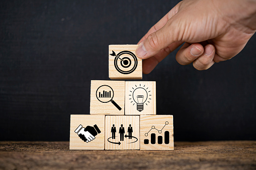 Hand putting print screen dart and target board wooden cube with magnifier glass graph and cog. Target of investment and business concept.