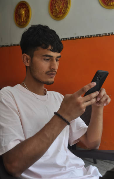 istock A handsome Indian young guy using his phone while sitting over chair in indoors 1367976907