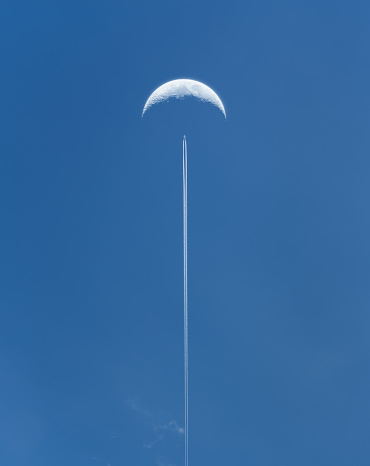 An aeroplane flies past the Moon. Composite image.