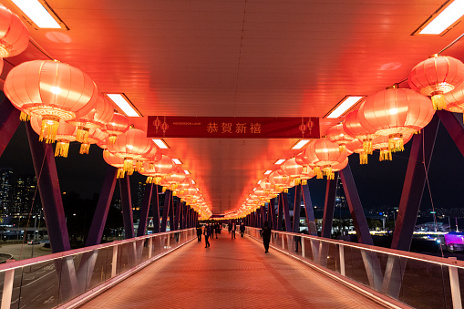 Hong Kong - January 31, 2022 : Pedestrians on a footbridge decorated with red lanterns ahead of the Chinese New Year, the Year of the Tiger, in Central, Hong Kong.