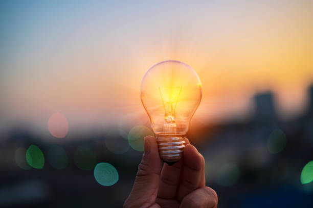 istock Man hands holds a house light bulb at sunset 1367977138