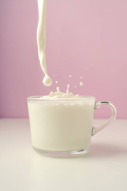 istock Milk is poured into a transparent cup on a purple background. 1367978002