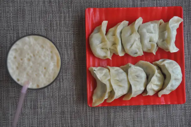 Photo of Overhead view of veg momos (Nepalese dumpling) with lassi over gray background