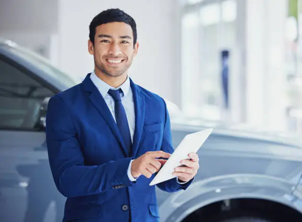 Photo of Cropped portrait of a handsome young male car salesman working on the showroom floor