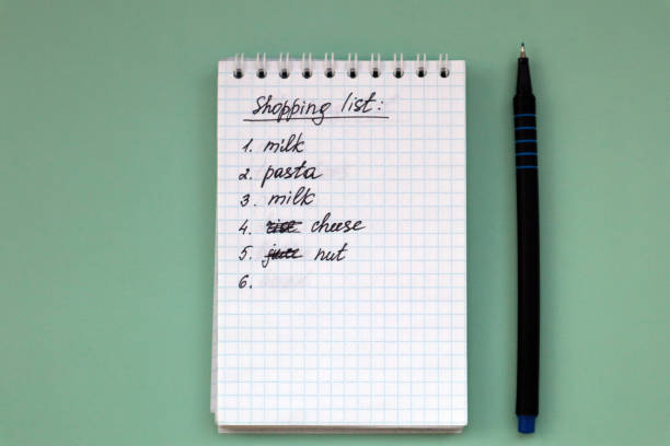istock Notebook with shopping list on green background and pen with copy space. 1367980410