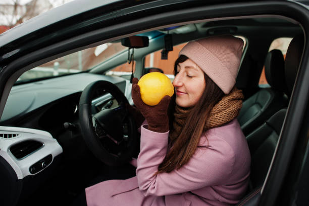 istock Young woman sit in car and sniffs a lemon at winter. 1367982323