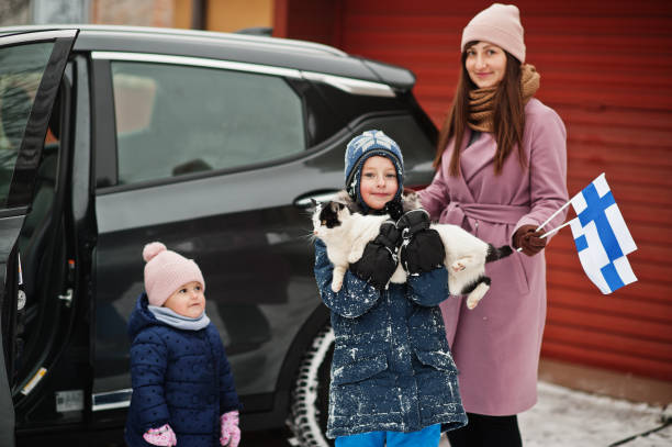 kids with cat on hands against car in the yard of house at winter. mother hold flag of finland. - domestic car color image horizontal car imagens e fotografias de stock