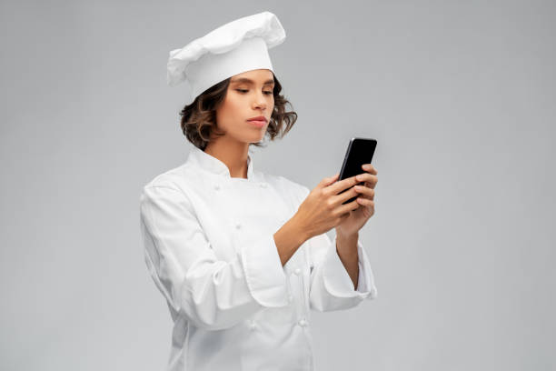 istock female chef in toque with smartphone 1367983657