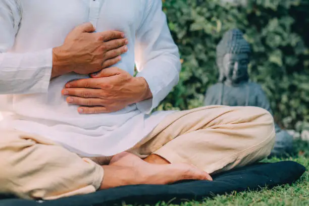 Male therapist performing reiki therapy self-treatment holding hands over his stomach. Alternative therapy concept.