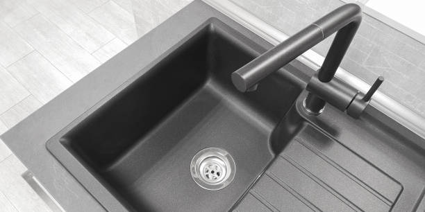 istock Close-up top view integrated single basin bowl sink with drainboard, dark color. Wing for drying utencil with grooves for draining water. Mixer tap of same material, neutral light kitchen background. 1367986685