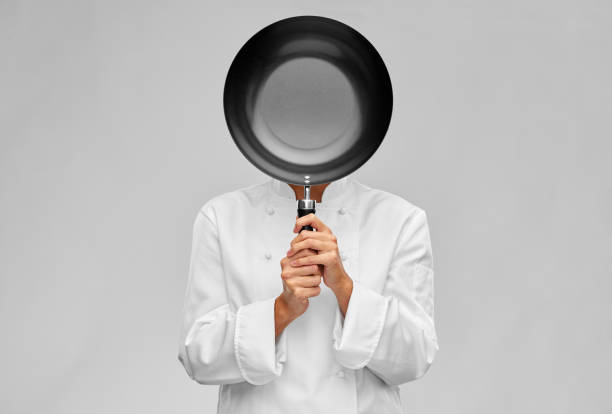 istock female chef covering her face with frying pan 1367986724