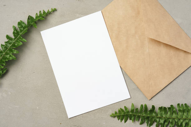 istock Paper envelope with white blank paper note and plant leaves on table 1367987033