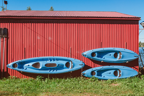 Three kayaks and paddles are hanging on the wall to dry. Storage of water sports and tourist equipment