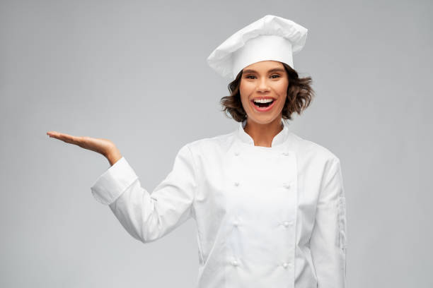 smiling female chef holding something on hand cooking, advertisement and people concept - happy smiling female chef holding something on palm of hand over grey background chefs whites stock pictures, royalty-free photos & images