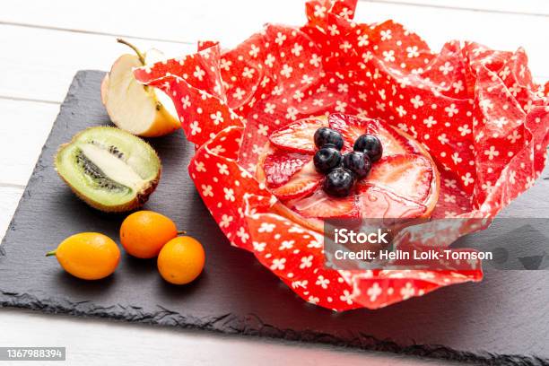 Take Away Cake Inside Homemade Beeswax Wraps Wrapping Food In Handmade Beeswax Wrap Cloth Indoors Alternative For Plastic Using Iron Machine To Melt Beeswax Into Cotton Cloth Stock Photo - Download Image Now