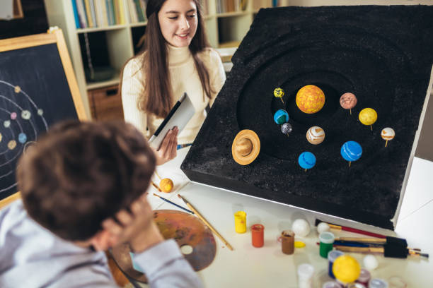 istock Happy school boy and girl  making school science project at home 1367989622