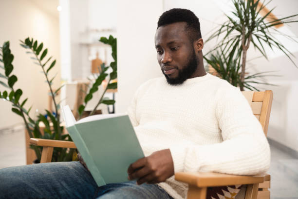 istock Young African American reading and relaxing at home 1367990041