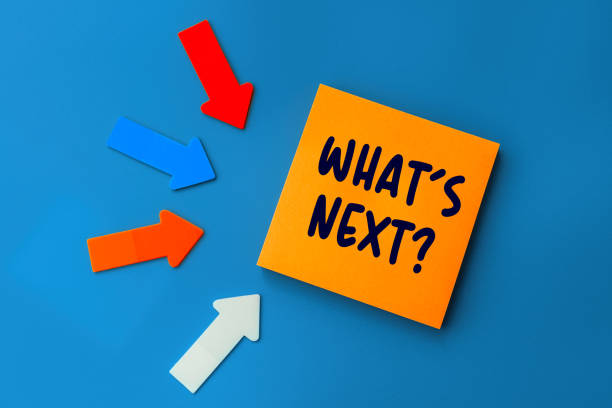 istock What's Next - concept of text on sticky note. Orange square sticky note and colorful arrows on blue background, top view 1367990095