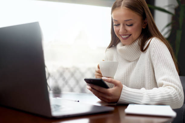 istock Happy beautiful girl using mobile phone while drinking coffee in cafe indoors 1367990314