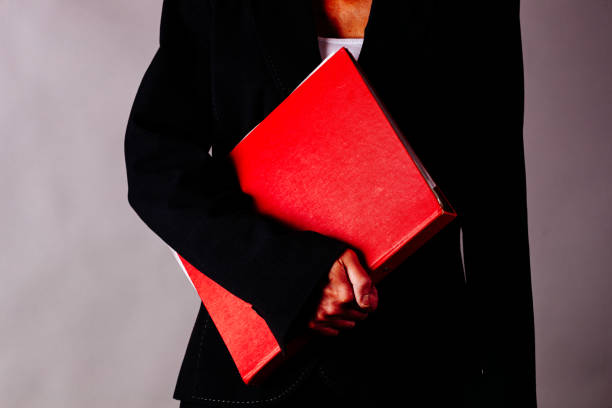 Mature business woman holding a folder in front of a plain background.