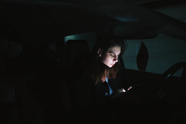 zmartwiona kaukaska nastolatka, siedząca w samochodzie i korzystająca z telefonu komórkowego - teenager dark pensive emotional stress zdjęcia i obrazy z banku zdjęć