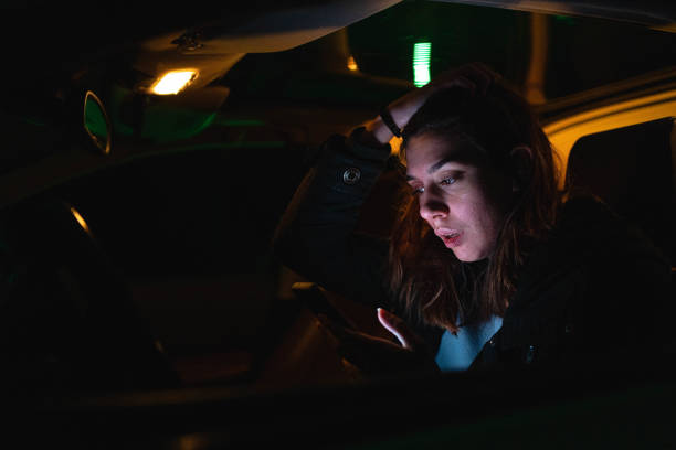 zmartwiona i maltretowana nastolatka, siedząca w samochodzie i korzystająca z telefonu komórkowego - teenager dark pensive emotional stress zdjęcia i obrazy z banku zdjęć